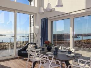 a dining room with a table and chairs and large windows at 8B Carrigreich in Tarbert