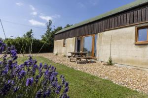 a building with a picnic table and purple flowers at The Dutch Barn in Stratton Audley