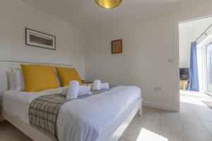 a white bedroom with a large bed with yellow pillows at The Dutch Barn in Stratton Audley