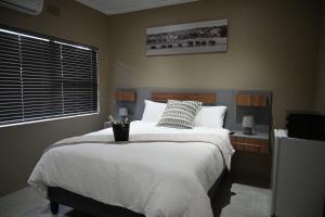 a bedroom with a large white bed and a window at 49 Sannaspos in Bloemfontein +2 photos