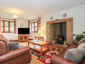 a living room with a couch and a fireplace at Byne Brook Cottage in Wistanstow