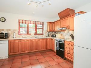 a kitchen with wooden cabinets and a white refrigerator at Byne Brook Cottage in Wistanstow