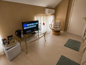a living room with a television and a glass table at Hotel Kamelia in Varna City