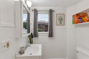 a white bathroom with a sink and two windows at Center Field All Star Baseball Rentals in Oneonta