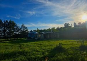 a tent in a field with the sun in the sky at Kupolinis namelis Miško Pašvaistėje in Balneliškiai