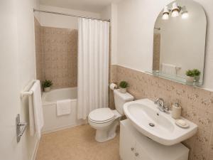 a white bathroom with a toilet and a sink at Aux Coquelicots in Saint-Honoré-les-Bains