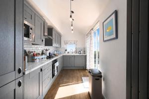 a large kitchen with white cabinets and a sink at Driftwood Cottage by Bloom Stays in Folkestone +16 photos