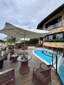 a patio with a table and an umbrella next to a pool at Divi-Divi Praia Hotel in Natal