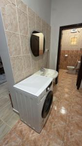 a bathroom with a toilet and a washing machine at v2 غرفة وصالة in Al Wajh