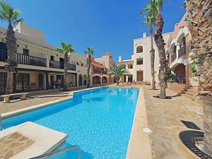 a swimming pool in a courtyard with palm trees and buildings at Harbour Lights IV in Villaricos