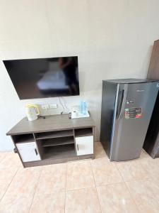 a tv and a desk with a refrigerator in a room at Amaya Bloom Resort & Spa in Pattaya