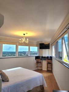 a bedroom with a bed and a chandelier and windows at Hotel Itália in Paranavaí