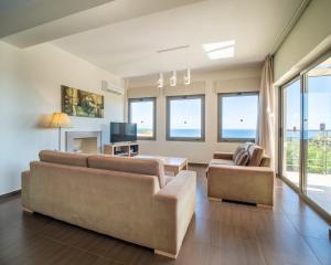 a living room with two couches and a tv at Villa Ilias in Skala
