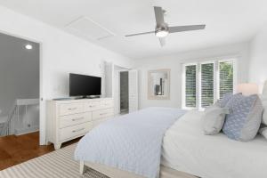 a white bedroom with a bed and a flat screen tv at 774 Spinnaker Beach House in Seabrook Island