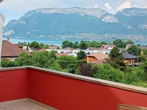 a red balcony with a view of a town and mountains at VUE LAC LODGES in Sévrier