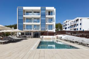 a hotel with a pool and chairs and a building at Sol Bahía Ibiza Suites in San Antonio