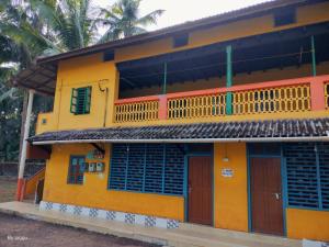 a yellow house with red doors and windows at Totadamane in murdeshwar in Māvalli