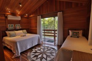 two beds in a room with a window at Chalé dos Lagos Ecoresort in Mandaguaçu