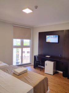 a bedroom with a bed and a desk and a television at Hotel Itália in Paranavaí