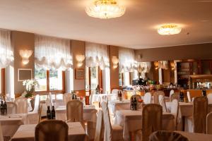 a restaurant with white tables and chairs and windows at Hotel Lido in Ledro