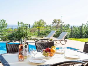 a table with a bowl of fruit and wine bottles at Villa Joya by Villa Select in Skala