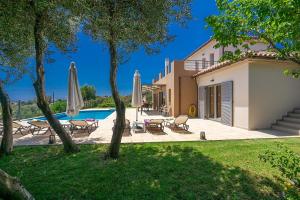 a villa with a swimming pool with umbrellas at Villa Joya by Villa Select in Skala