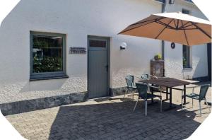a table with an umbrella next to a building at Gîte 2 pers - La Pommeraie - Le Coin Ardenne in Sainte-Ode