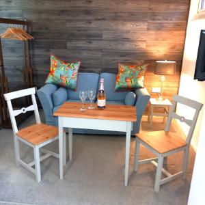 a blue couch with two chairs and a table with a bottle of wine at Thistles Studio - Near Newark & Stubton Hall in Claypole