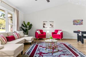 a living room with red chairs and a piano at Splash & Relax Games WiFi BBQ Fire Pit Boat Lake in Royal Palm Beach