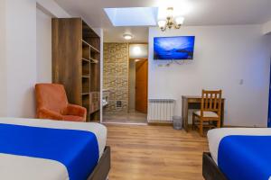 a bedroom with two beds and a desk and a chair at Estancia San Pedro Hotel in Cusco