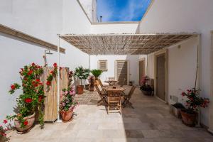 a patio with a table and chairs and flowers at Miria B&B in Castrignano del Capo