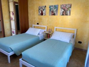 two beds in a room with paintings on the wall at Domu Bella in Decimomannu