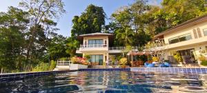 a house with a swimming pool in front of a house at Unique panoramic sea view pool villas in Phuket