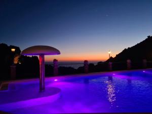 a swimming pool with purple lighting in front of a sunset at Aligia Chalet in Nebida