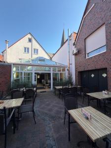 eine Terrasse mit Holztischen und -stühlen und ein Gebäude in der Unterkunft Da‘ Amici in Horstmar