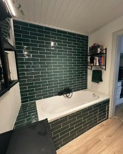 a bathroom with a bath tub with a green tile wall at Jimy Hendrickx in Boom +14 photos