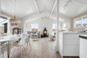 a white kitchen and living room with a table and chairs at LN2048-Hjorring-Havmanden-6 in Kærsgård Strand +12 photos