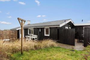 a black house with a table and chairs in a yard at LN2048-Hjorring-Havmanden-6 in Kærsgård Strand