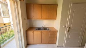 a kitchen with a sink and wooden cabinets and a door at Kalamata Deluxe Suite By AGGELOS in Kalamata +16 photos