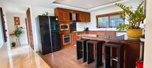 a kitchen with a black refrigerator and wooden cabinets at Unique panoramic sea view pool villas in Phuket