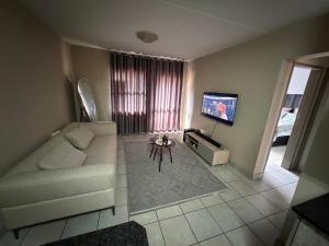 a living room with a white couch and a tv at Zoe in Centurion