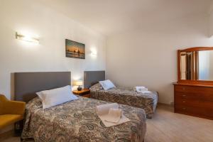 a hotel room with two beds and a dresser at Villa Fatima by Villa Select in Galé +21 photos