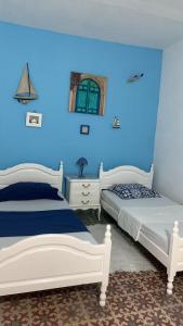 two beds in a room with blue walls at Nadia Babay in Dar Salah Bey