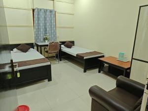 a room with two beds and a table and a couch at Basudev Lodge in Dibrugarh