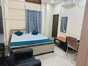 a bedroom with a bed and a desk and a chair at Basudev Lodge in Dibrugarh