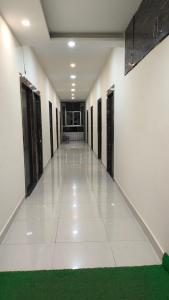 an empty hallway with doors and a green carpet at Basudev Lodge in Dibrugarh +7 photos