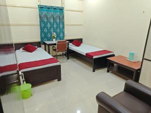 a room with two beds and a table and a couch at Basudev Lodge in Dibrugarh