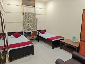 a room with two beds and a table and a bench at Basudev Lodge in Dibrugarh