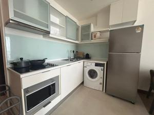 a small kitchen with a refrigerator and a washing machine at The Astra Residence in Chiang Mai