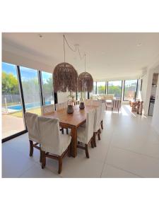 a dining room with a wooden table and chairs at COSTA ESMERALDA S3 para 10 pileta y jardín privados in Pinamar
